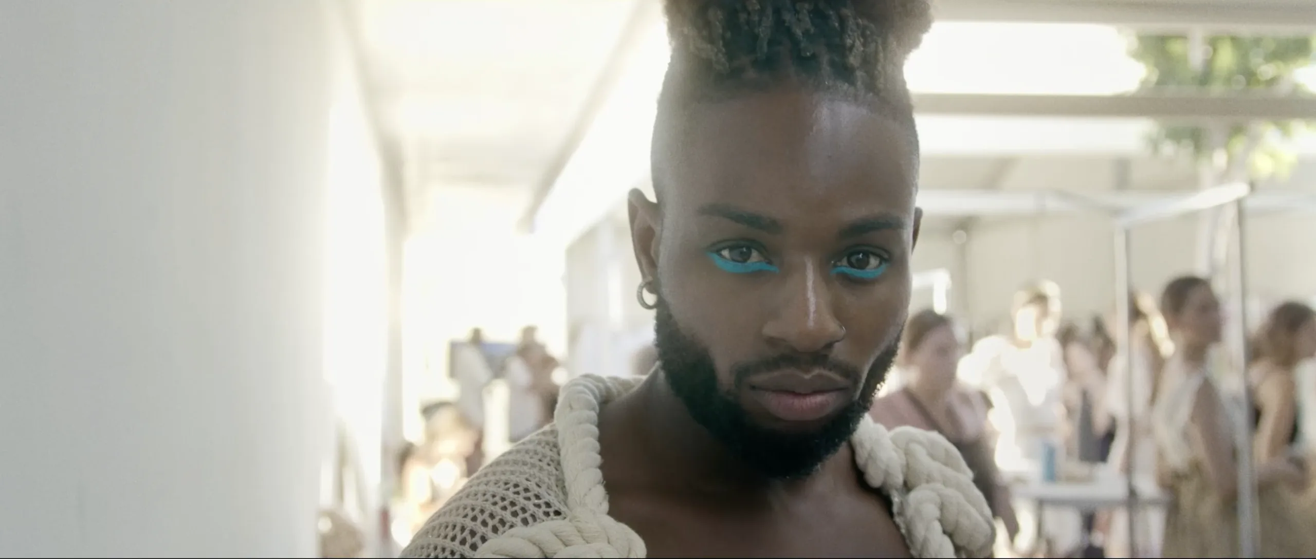 Retrato de un modelo con maquillaje azul y una prenda de punto en el backstage de ADLIB Ibiza