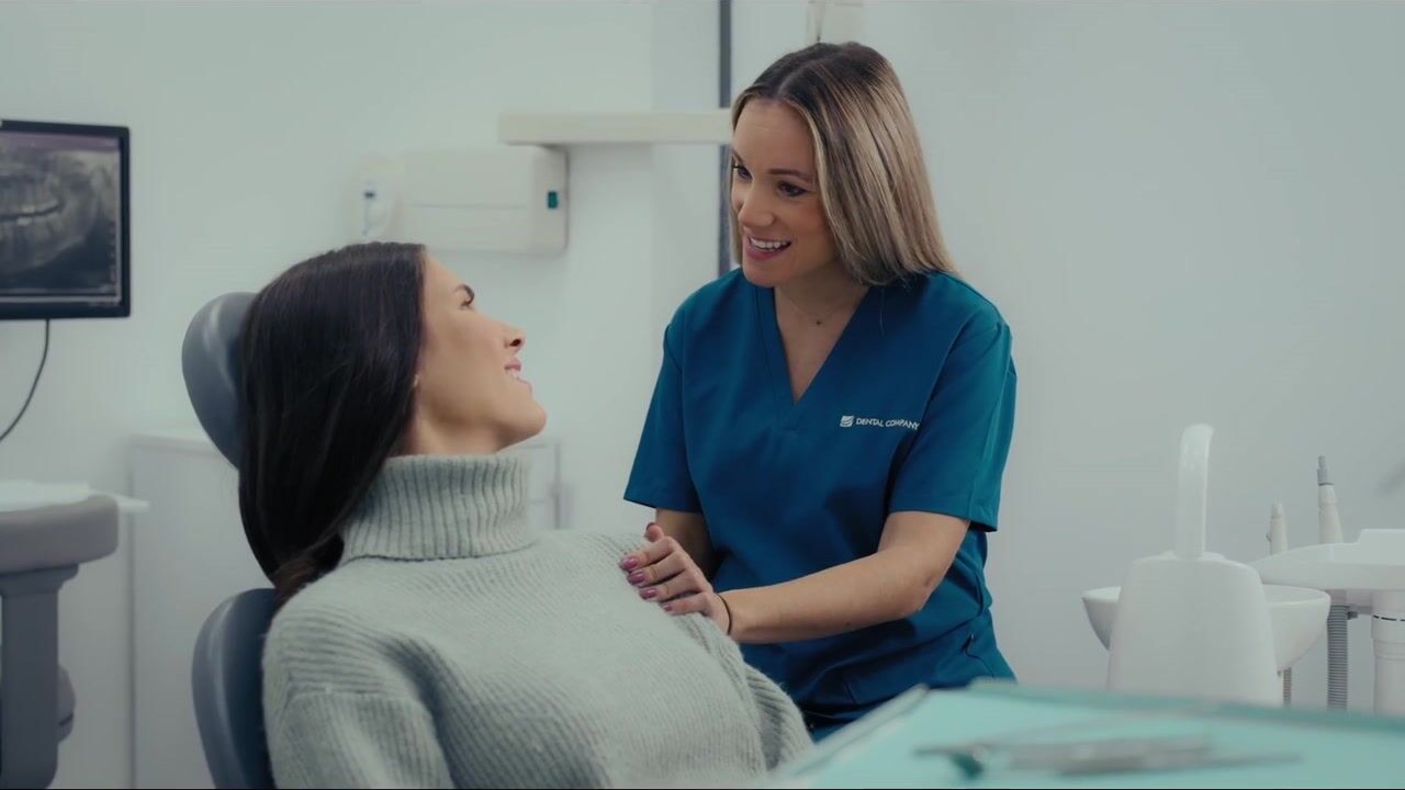 Una profesional de Dental Company conversa con una paciente y apoya la mano en su hombro